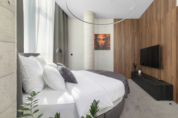A modern bedroom with a bed, a TV, a plant, and a wooden wall.