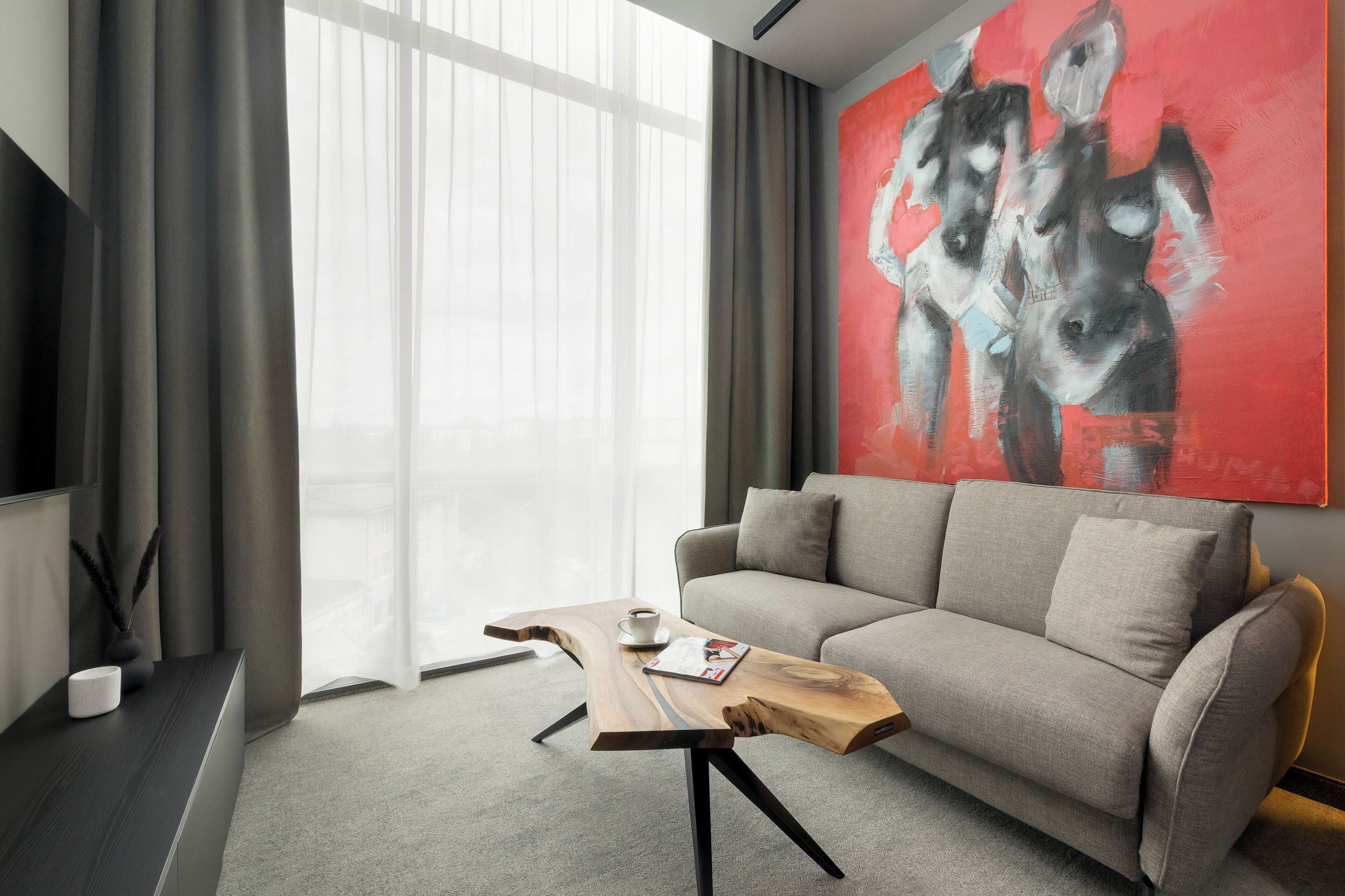 Un salon moderne avec un canapé, une table basse et un grand tableau abstrait.