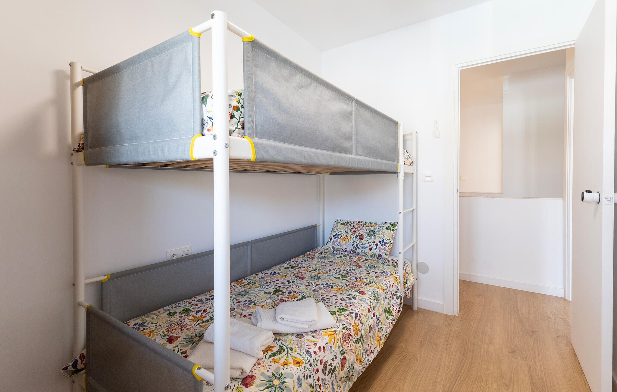A bunk bed with a floral bedspread and a white towel on the lower bunk.