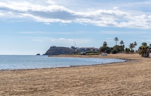A beach with a rocky outcrop, a lighthouse, and palm trees. - 3 bedroom awesome home in Puerto de Mazarrón (Puerto de Mazarrón)