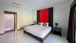 A modern hotel room with a large bed, a red accent wall, and a small bedside table with a lamp. - The Lavana Bali Radiance Arjuna Villa Seminyak (Bali)