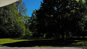 An outdoor patio with a table and chairs, surrounded by a concrete floor and a grassy area. - Lodging in a garden near Fraispertuis City Park. (Rambervillers)