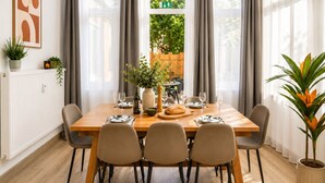 Comedor con mesa de madera preparada para cuatro personas, sillas alrededor y vista a zonas verdes.