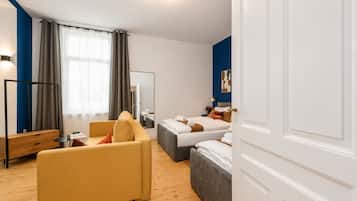 Ein Hotelzimmer mit einer Couch, zwei Betten, einem Spiegel, einem Nachttisch und einem Kleiderschrank.
