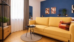 Una sala moderna con un sofá amarillo, una mesa redonda de centro, una estantería y arte abstracto en la pared.