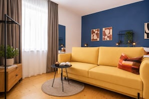 Una sala moderna con un sofá amarillo, una mesa redonda de centro, una estantería y arte abstracto en la pared.