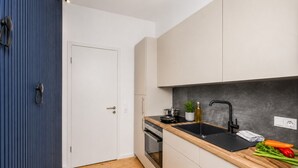 Una cocina compacta con encimera de madera, un lavabo negro y una estufa.