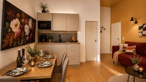 Una cocina moderna con comedor, un sofá rojo y un cuadro en la pared.