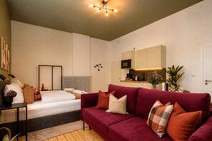 Una sala moderna con una cama, un sofá rojo y una zona de cocina.