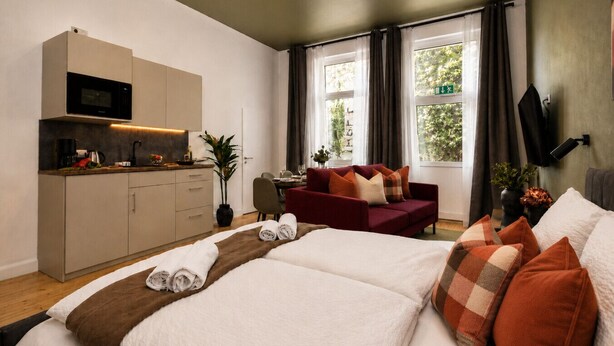 Une chambre d’hôtel comprenant un lit, un canapé, un coin repas, une cuisine et un téléviseur.