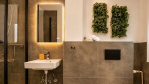 Une salle de bain avec un lavabo, un miroir, des toilettes et une décoration murale verte.