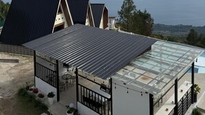 Un bâtiment moderne doté d’un toit plat, d’un patio entièrement vitré et offrant une vue sur le paysage environnant.