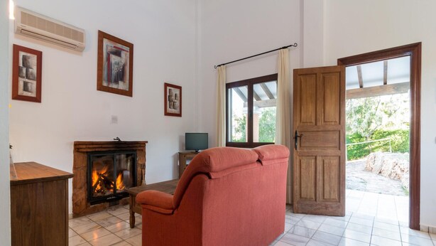 A living room with a fireplace, a sofa, a television, and a door leading outside. - Ibipozo Home for 6 Near Bolera Reservoir (Pozo Alcon)