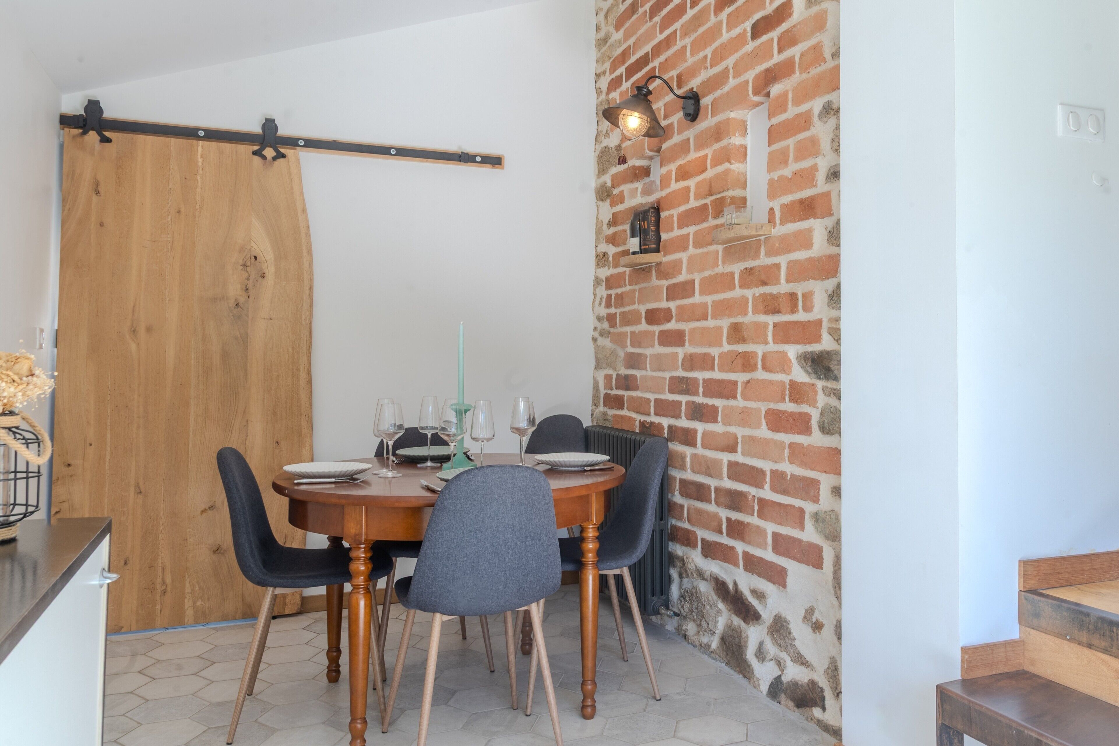 A dining area with a wooden table, chairs, and a brick wall.