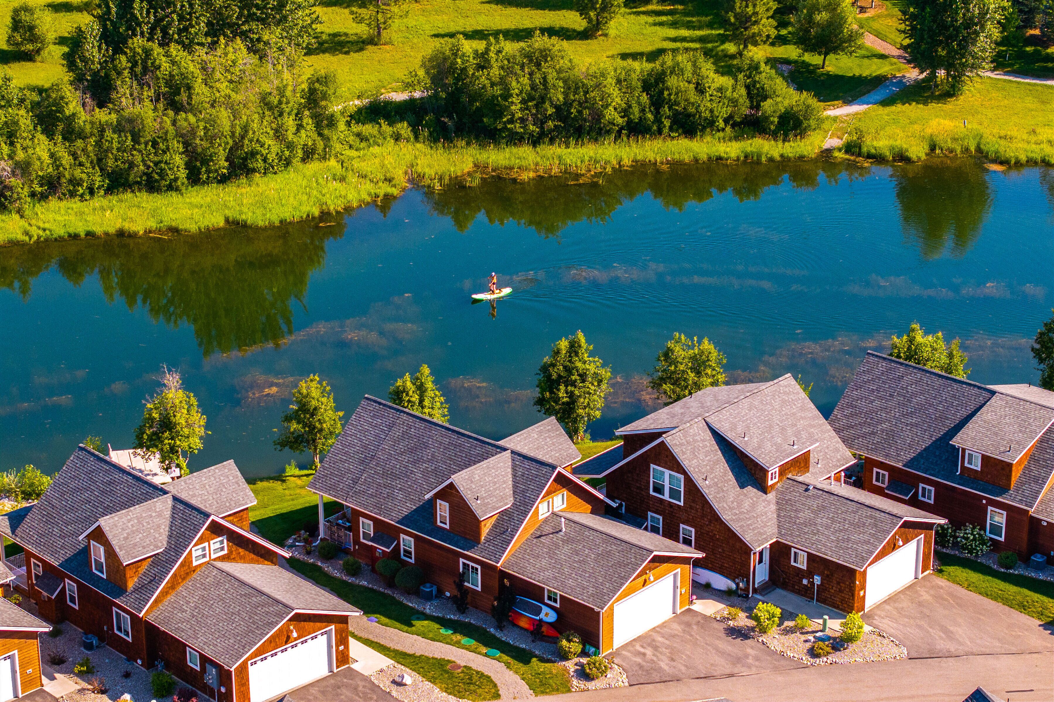 Un quartier résidentiel avec des maisons, un lac et une personne sur une planche à pagaie.
