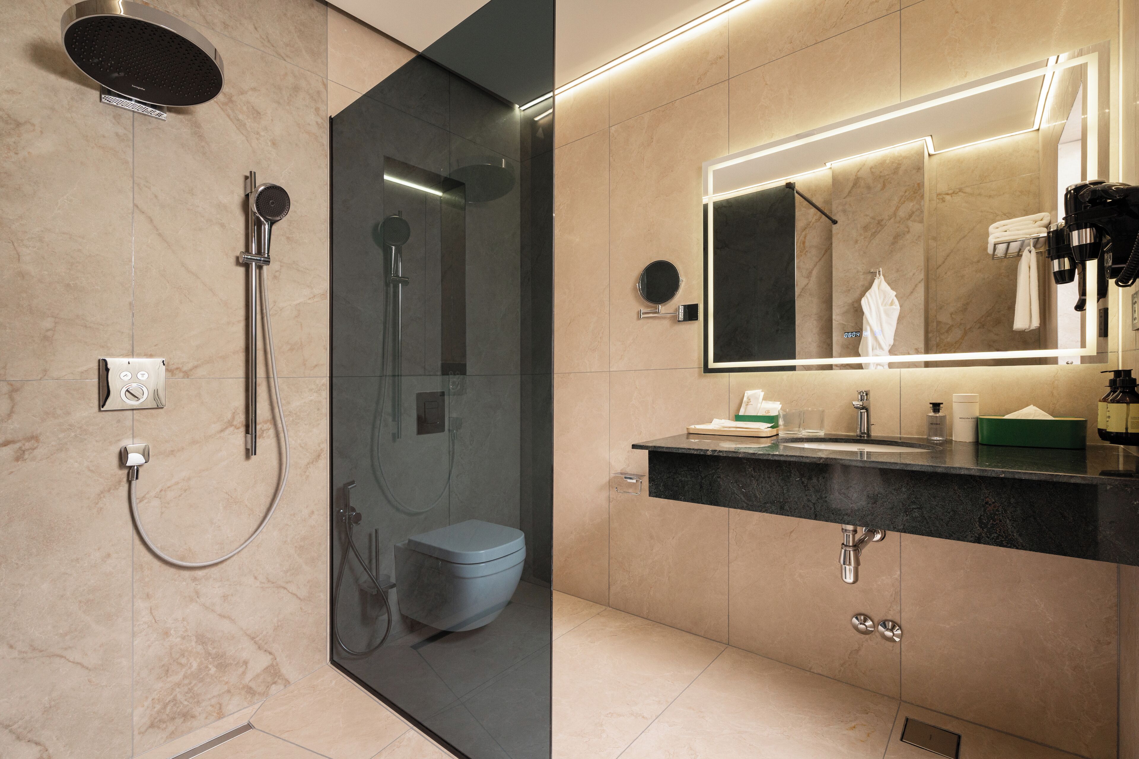 A modern bathroom with a glass-enclosed shower, a toilet, a vanity with a mirror, and a sink.