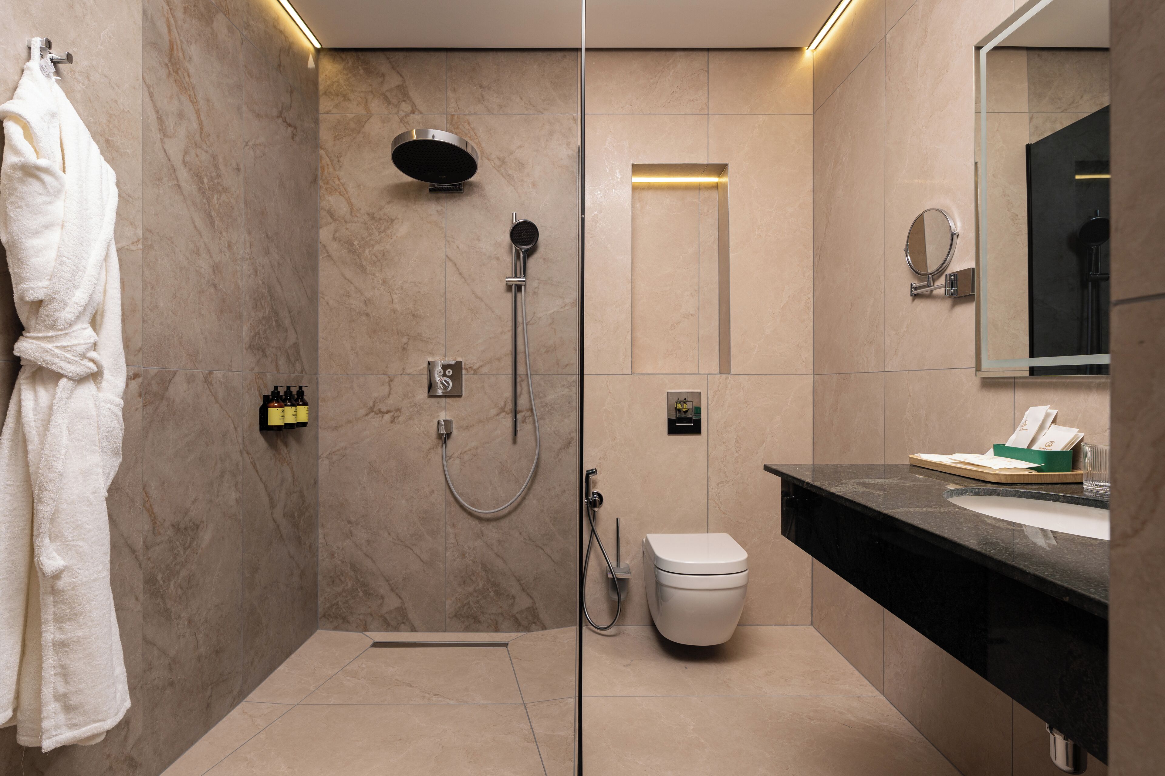 A modern bathroom with a glass-enclosed shower, a toilet, and a vanity with a mirror.