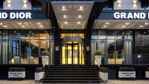 A hotel entrance with a revolving door, glass doors, and seating area outside. - Grand Dior (Tashkent)