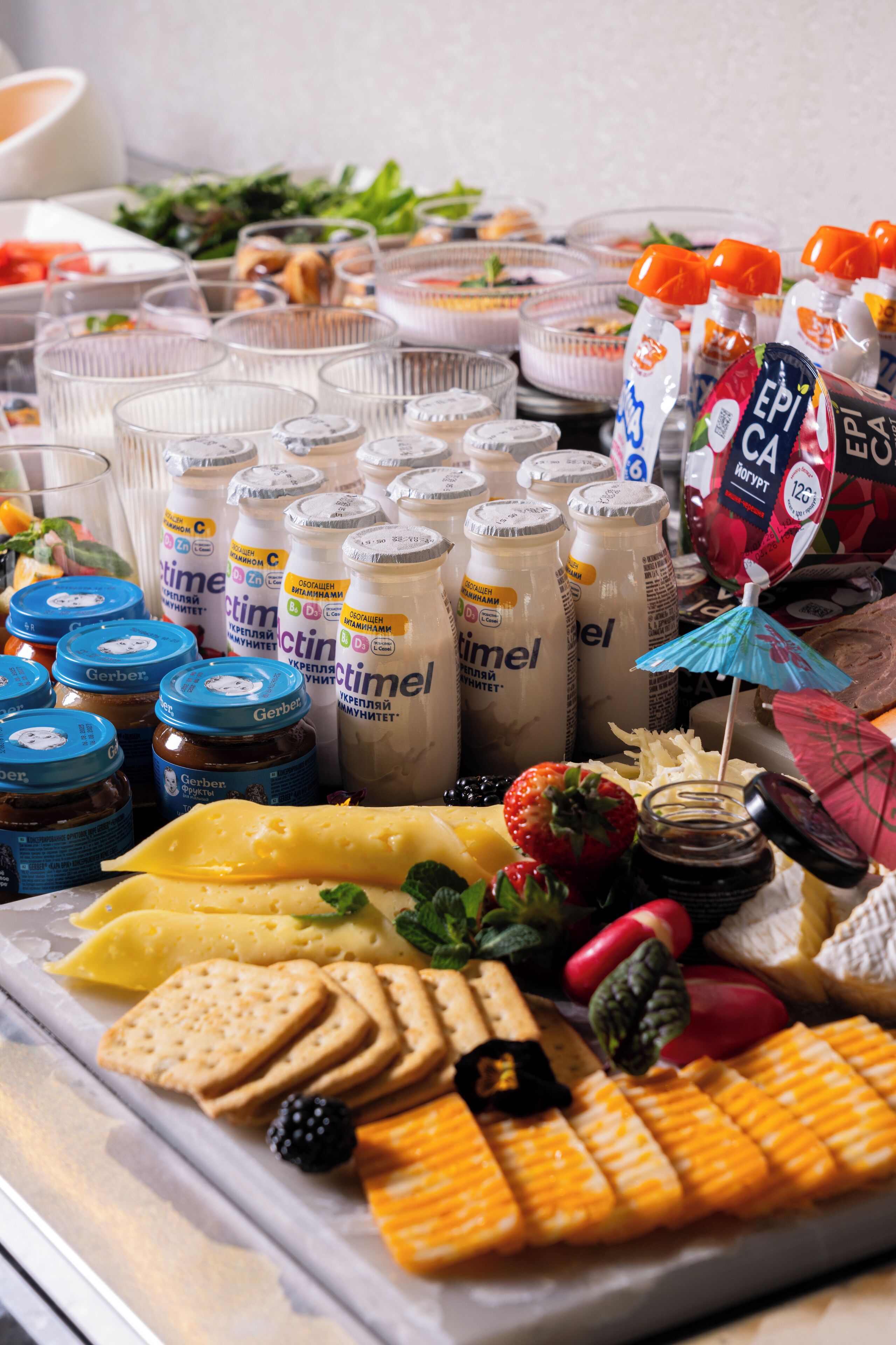 Un bufé con diversos alimentos y bebidas, incluyendo queso, galletas y botellas de jugo.