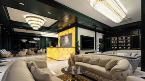 A luxurious lobby with a grand chandelier, plush seating, and a display of decorative plates. - Grand Dior (Tashkent)