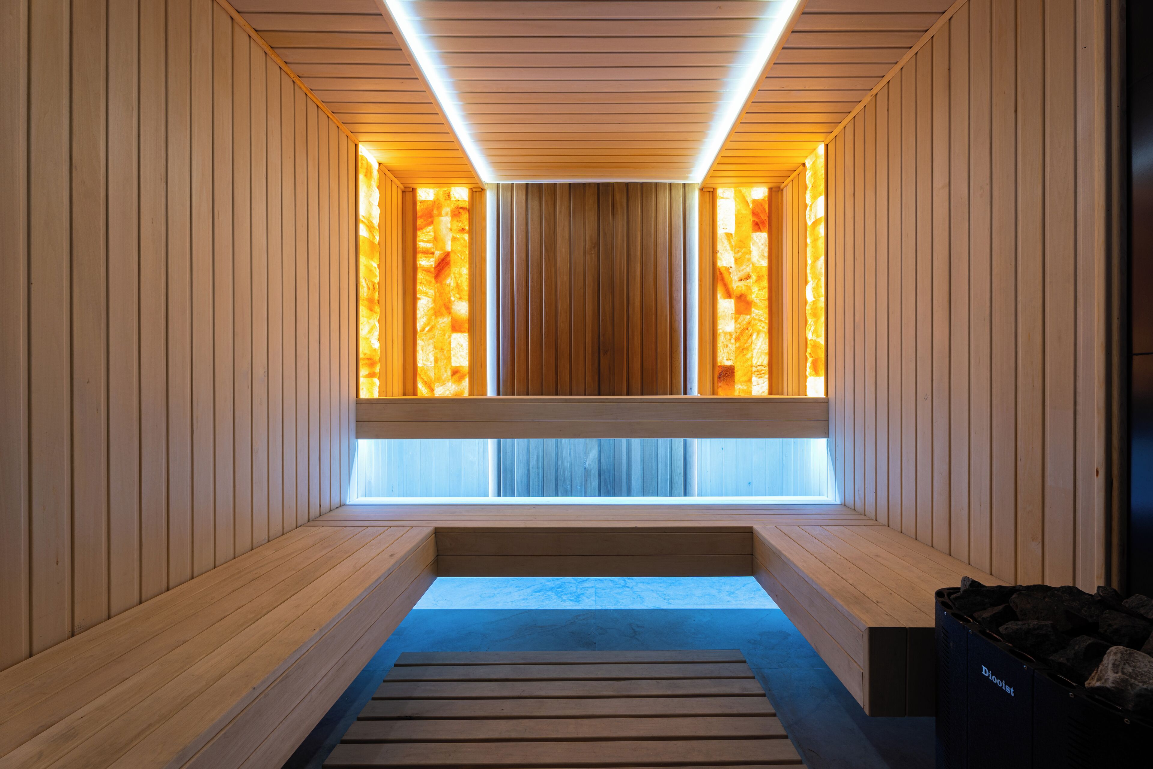 A sauna with wooden walls and benches, a central wooden divider, and a skylight.