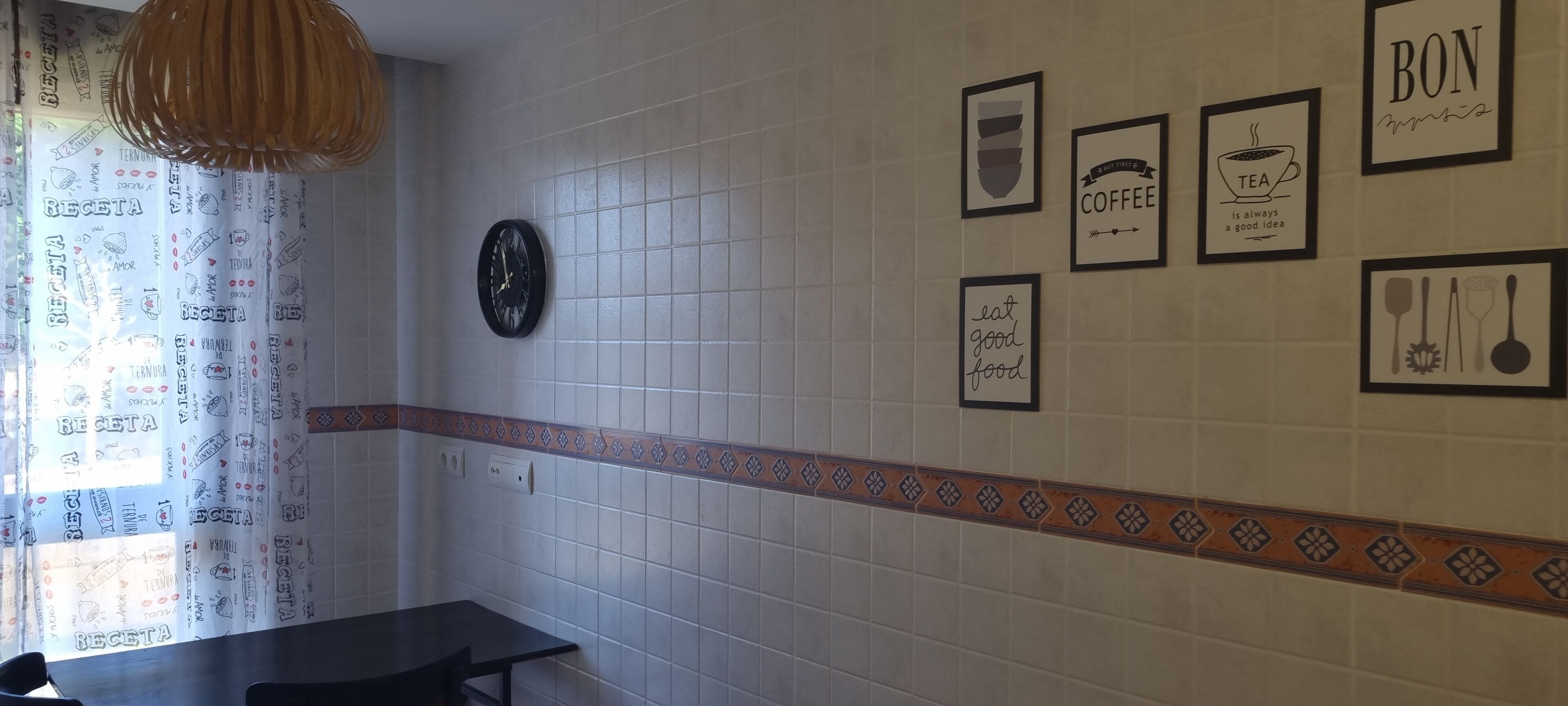 Een keuken met witte tegels, een klok en verschillende lijstjes met inspirerende citaten.