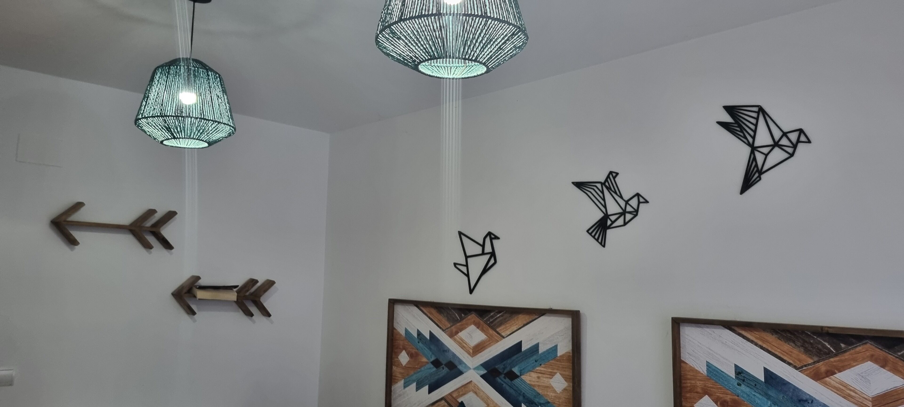 A room with geometric wall art, two hanging lamps, and wooden arrow decorations.