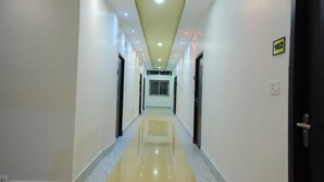 Un pasillo de hotel con suelo de mármol, paredes blancas e iluminación empotrada en el techo.