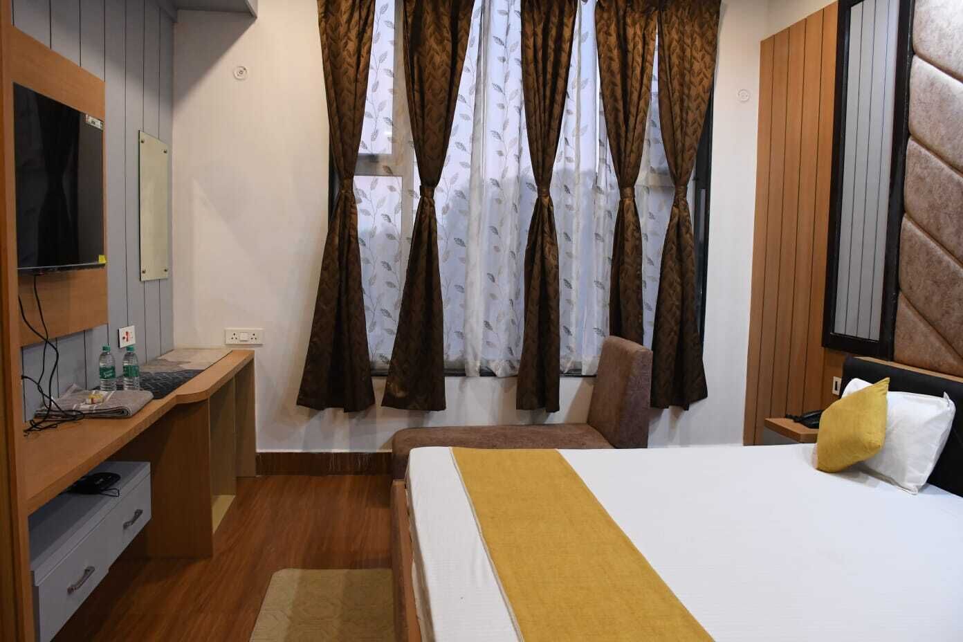 A hotel room with a bed, a desk, a chair, and a TV.