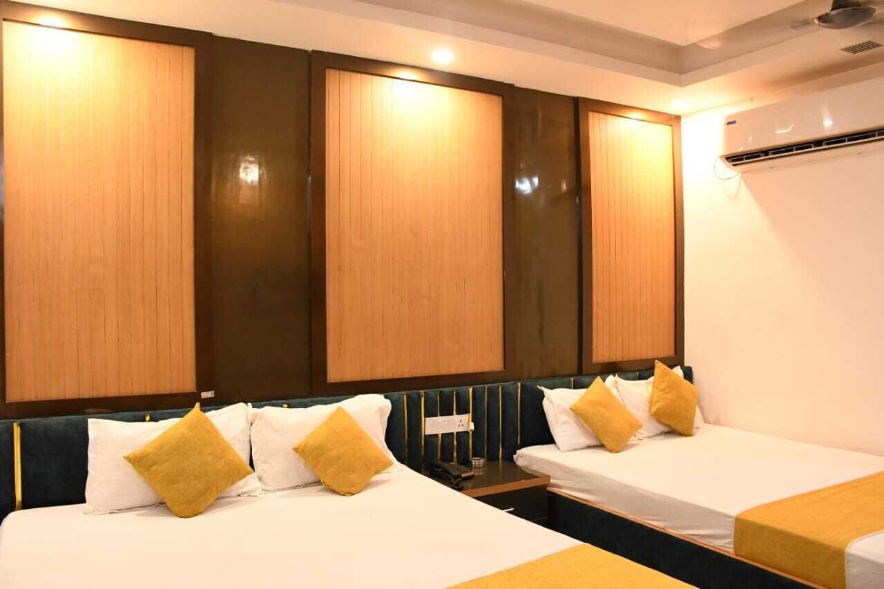 Quarto de hotel com duas camas, painéis de madeira nas paredes e aparelho de ar condicionado.