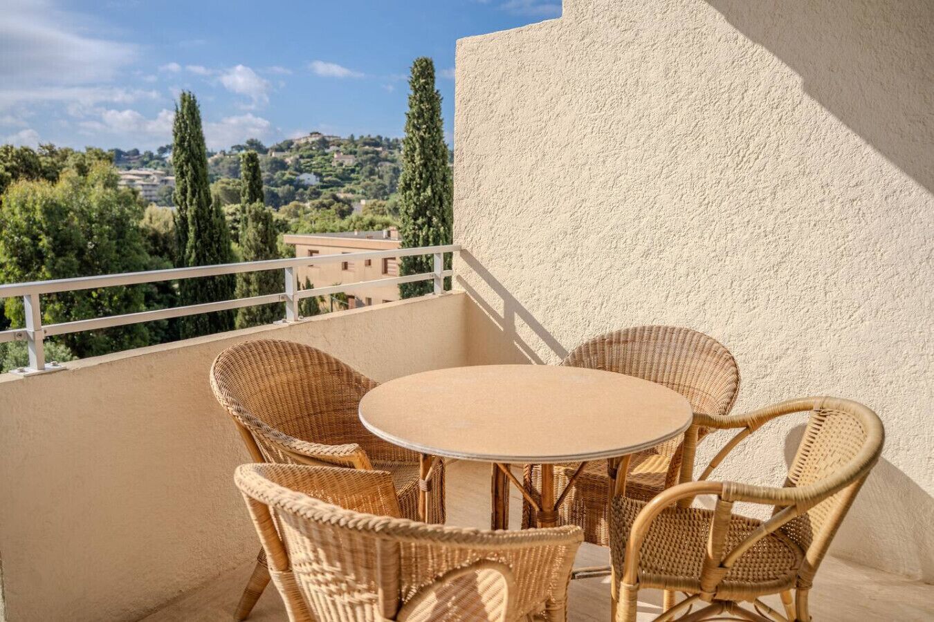 Un balcon doté de meubles en osier et offrant une vue sur un paysage vallonné.