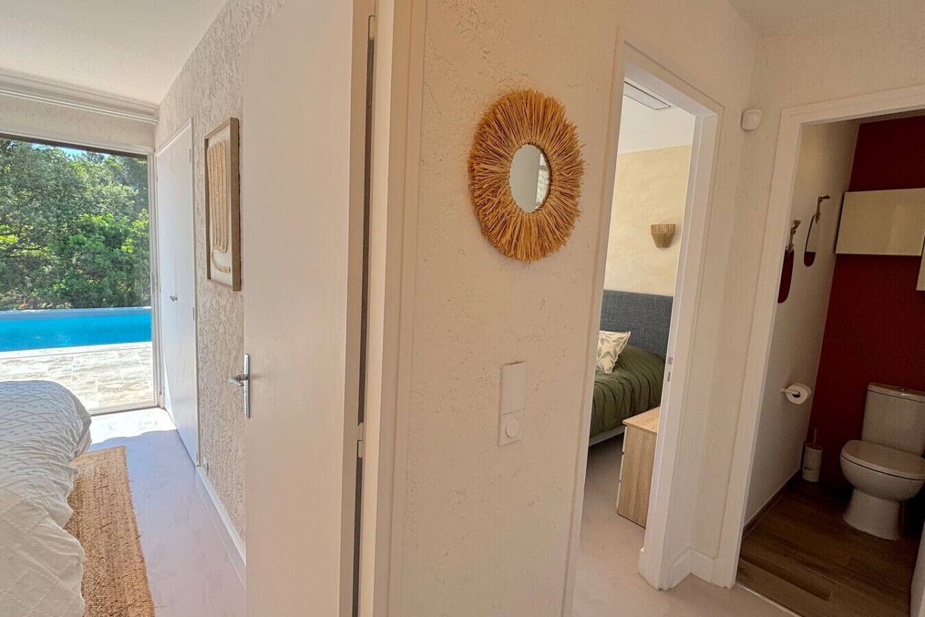Une chambre avec un lit, une porte donnant sur une salle de bain et une vue sur une piscine.