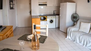 A compact kitchen with a washing machine, a refrigerator, and a dining area with a table set for two.