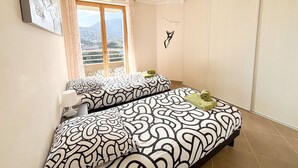 A bedroom with two beds, a window with a view, and a ceiling fan.