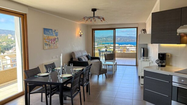 A modern living room with a dining area, a kitchen, and a balcony with a view.
