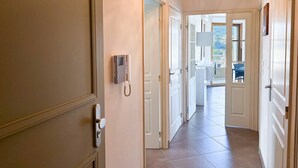 A hallway with a telephone, open doors leading to a balcony, and a view of the outside.