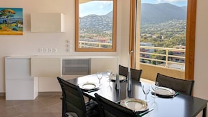 A dining area with a table set for two, a refrigerator, and a painting on the wall.