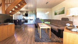 A modern living room with a wooden staircase, a sofa, a coffee table, and a TV. - Seepark Heidenholz, Plau am See (Plau am See)