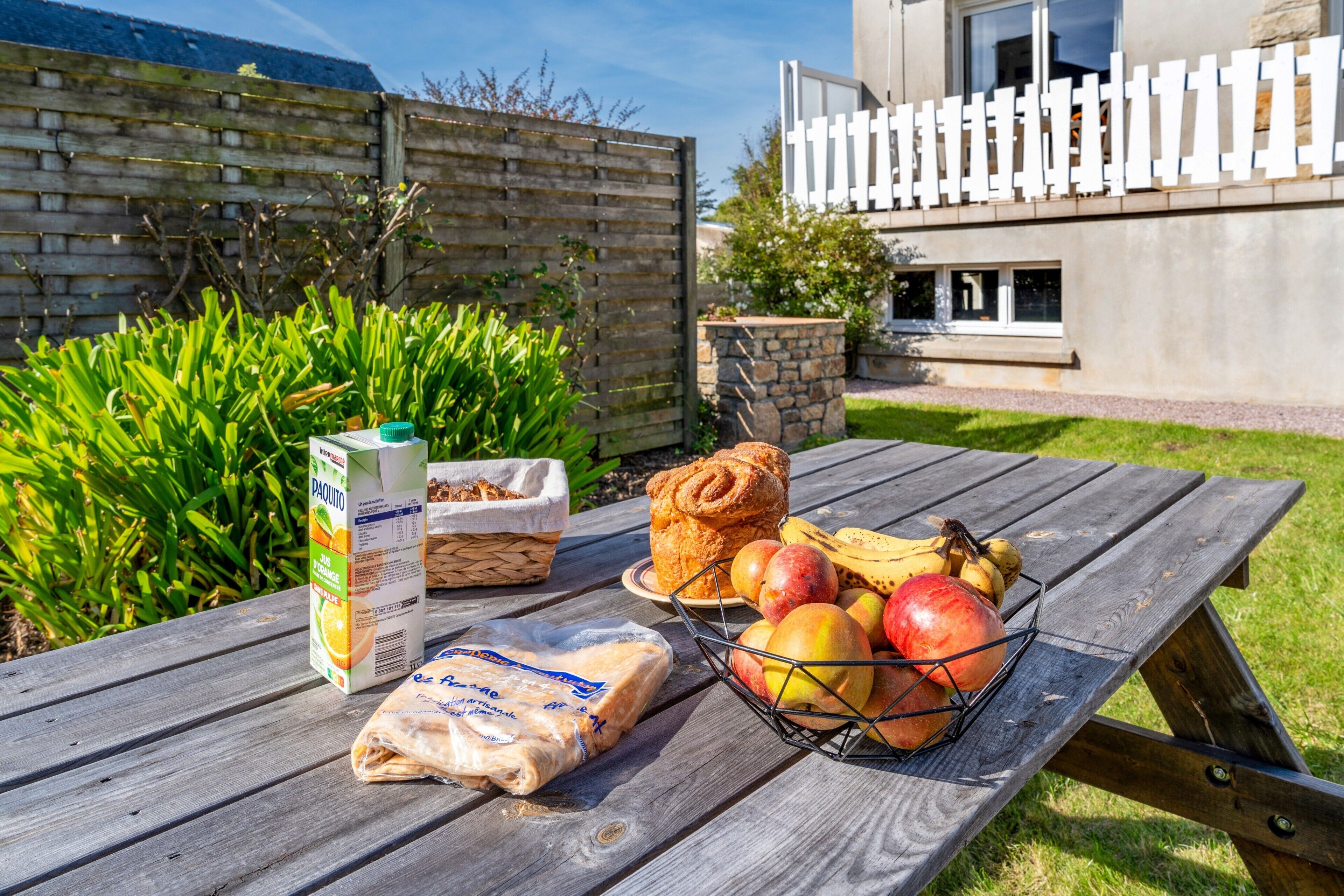 Ein Picknicktisch mit Lebensmitteln, einem Obstkorb und einer Saftpackung.