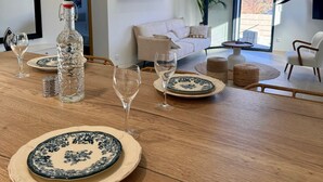 Comedor con mesa de madera dispuesta para cuatro, con platos blancos decorados con motivos florales azules.