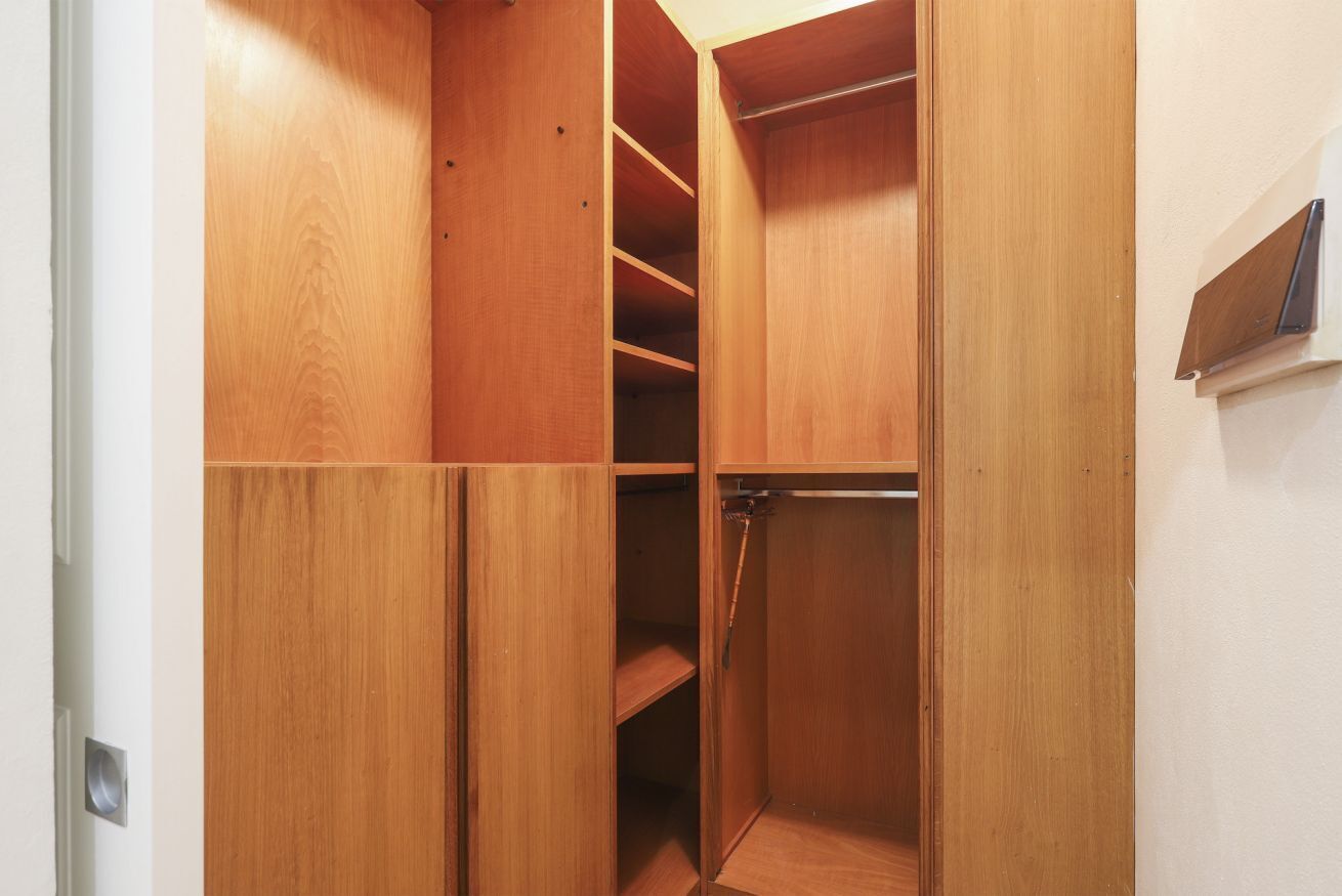 A wooden closet with multiple shelves and hanging space.