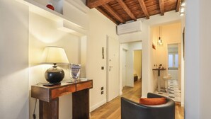 A modern living room with a wooden floor, a black leather chair, a table with a lamp, and a sign on the wall. - Lovely one bedroom near Signoria Square (Firenze)