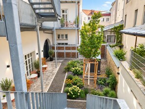 Un patio con una pérgola de madera, mobiliario exterior y diversas plantas.
