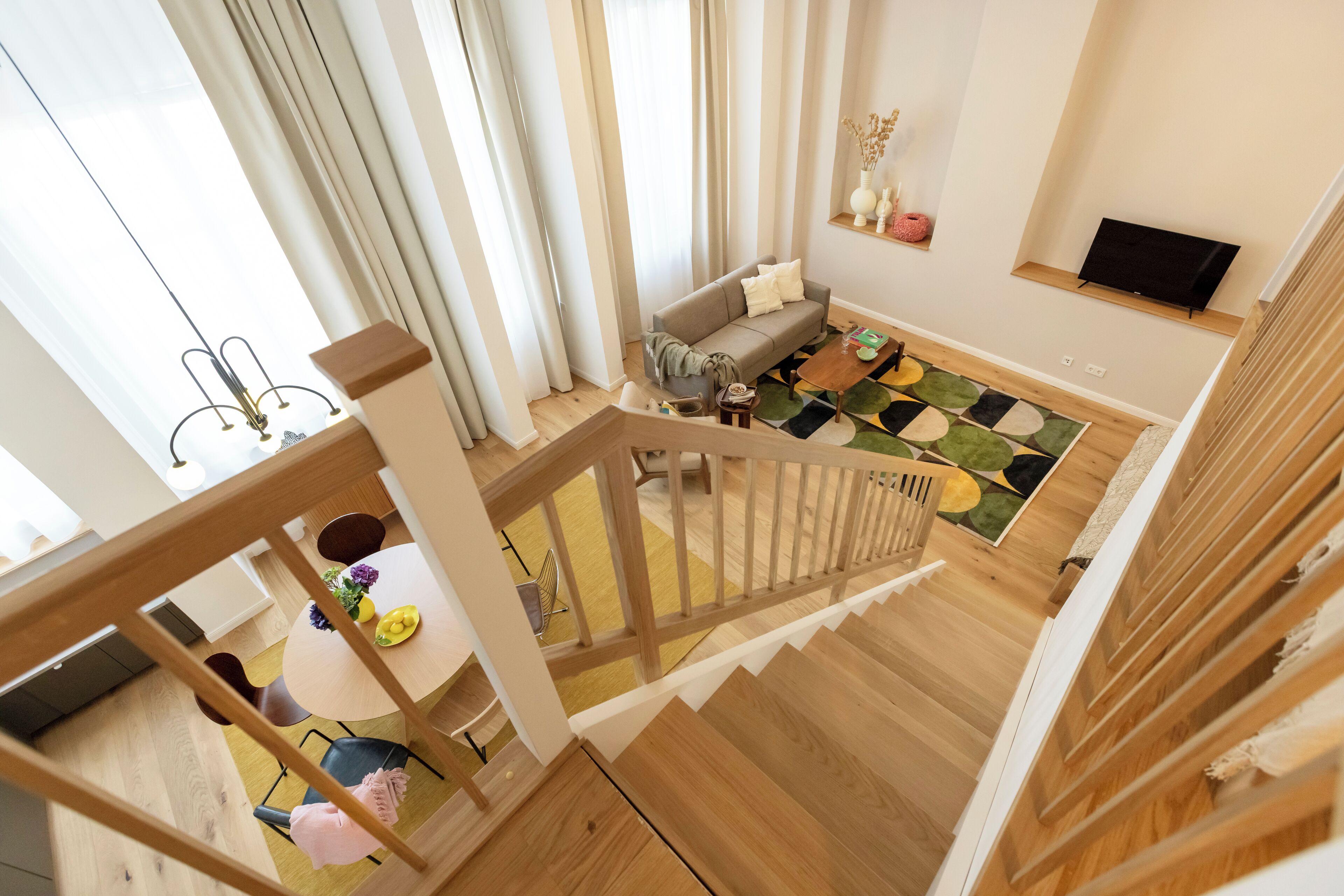 A modern living room with a wooden staircase, a sofa, a coffee table, and a TV.
