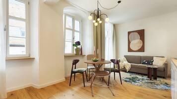 A dining area with a round table, chairs, a vase with flowers, and a chandelier.