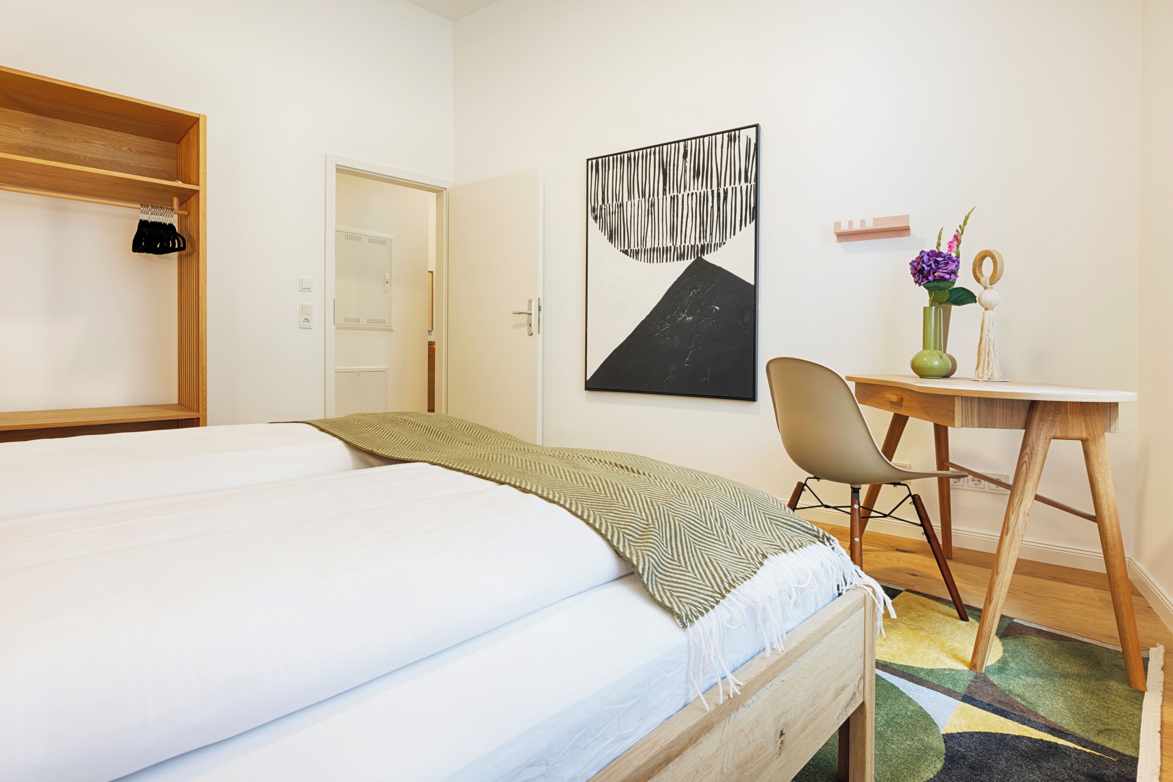 A bedroom with a bed, a desk, and a chair.