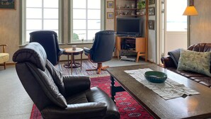 A living room with a leather sofa, two armchairs, a coffee table, a TV, and a bookshelf. - Lovely home in Fiksdalen with WiFi (Fiksdalen)