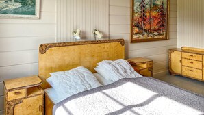 A bedroom with a wooden headboard, a bed with white linens, a nightstand, a dresser, and a painting on the wall. - Lovely home in Fiksdalen with WiFi (Fiksdalen)