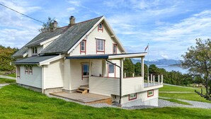 A two-story house with a balcony, a front porch, and a view of the water. - Lovely home in Fiksdalen with WiFi (Fiksdalen)
