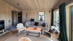 A cozy living room with a wooden interior, a sofa set, a coffee table, and a television. - 2 bedroom beautiful home in Gålå (Gålå)